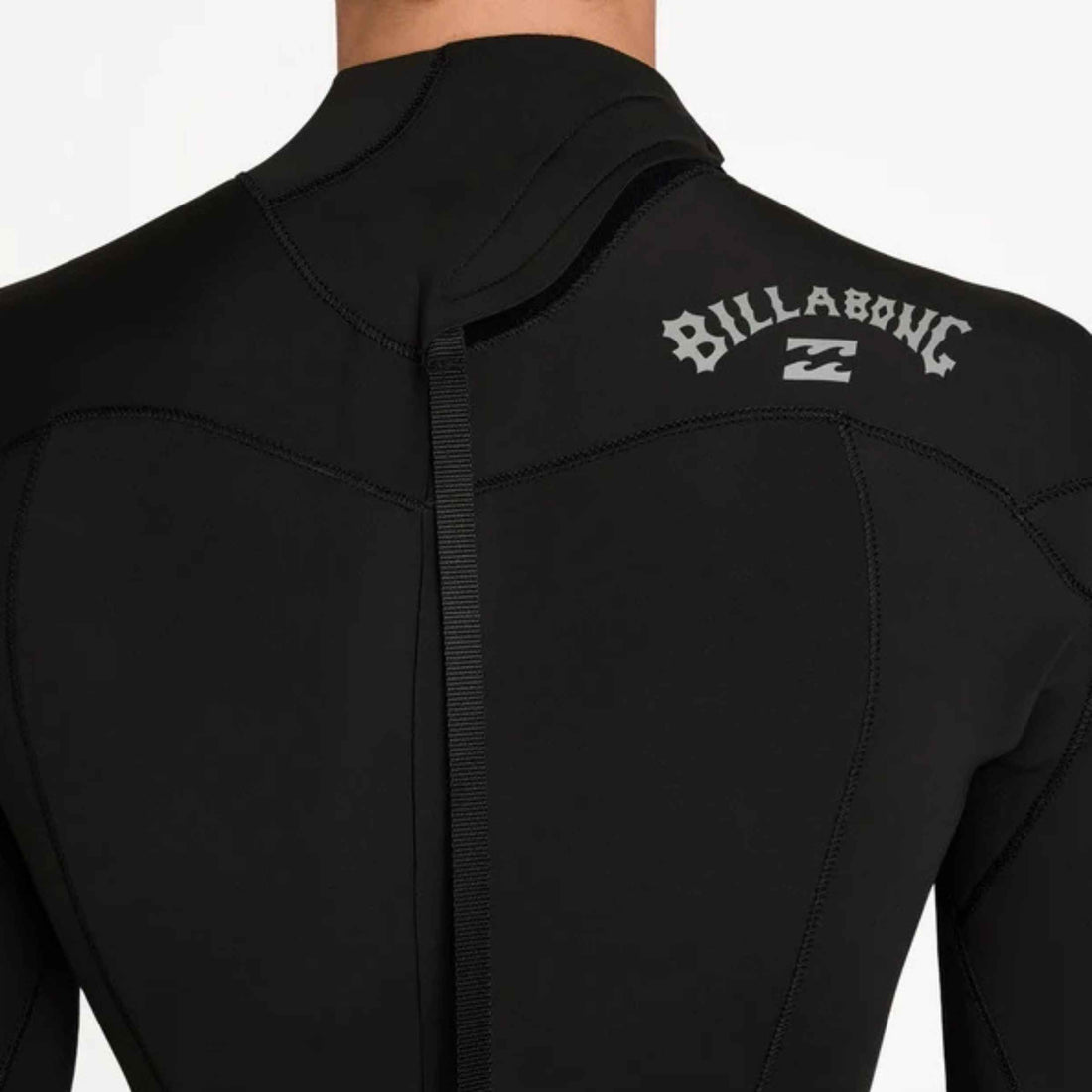 Close-up back view of a black Billabong wetsuit with a high collar and white Billabong logo on the upper back, shown on a model against a light gray background.