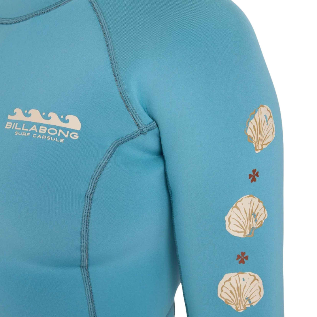 Close-up of a Billabong Surf Capsule long-sleeve wetsuit in a light blue color, featuring a white logo on the left chest and a vertical line of beige seashell and small red floral motifs on the right sleeve.