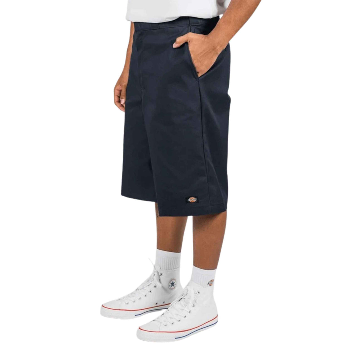 A person wearing dark navy knee-length shorts with side pockets, paired with white crew socks and white high-top sneakers, shown against a plain white studio background.