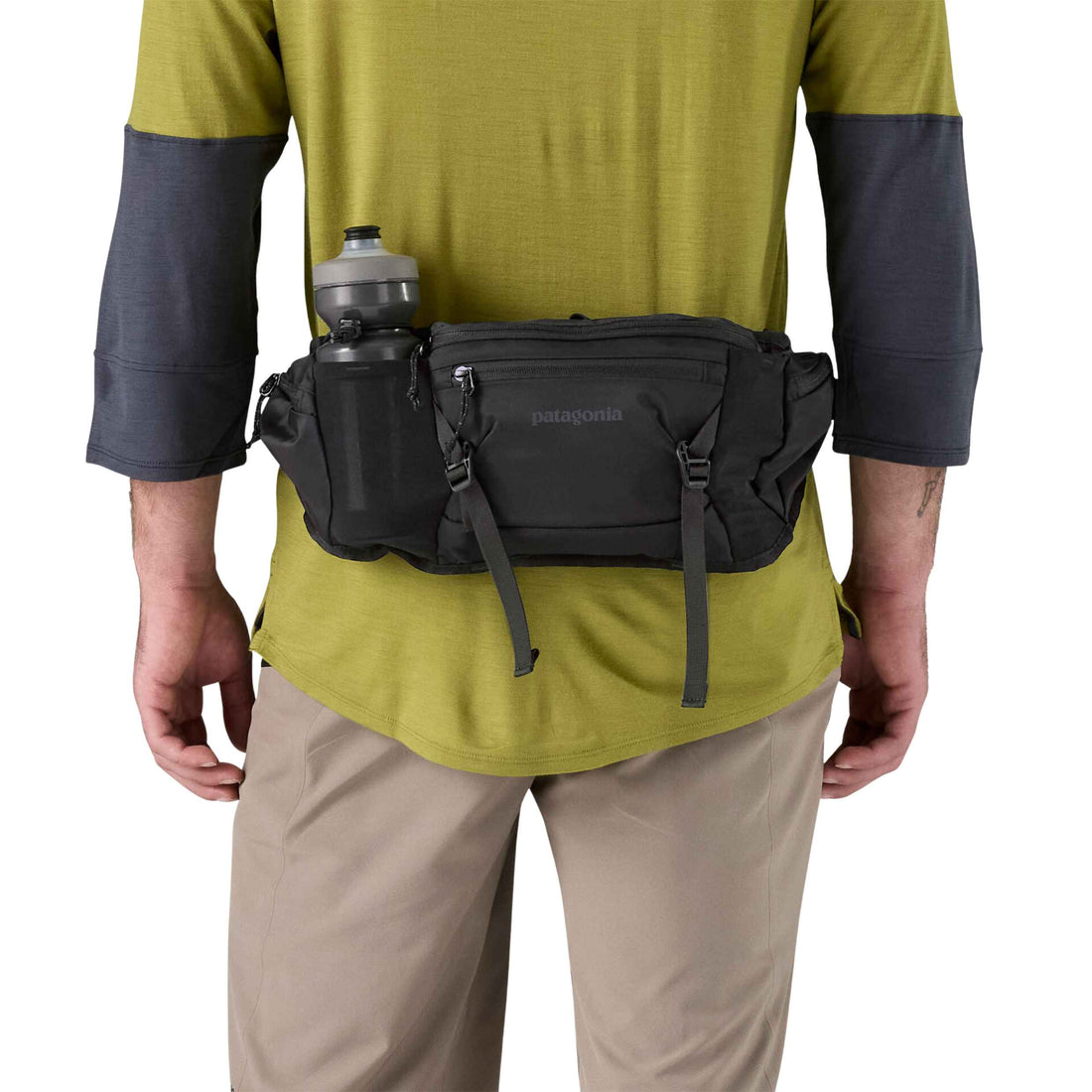 Person wearing a black Patagonia waist bag with a water bottle on a white background
