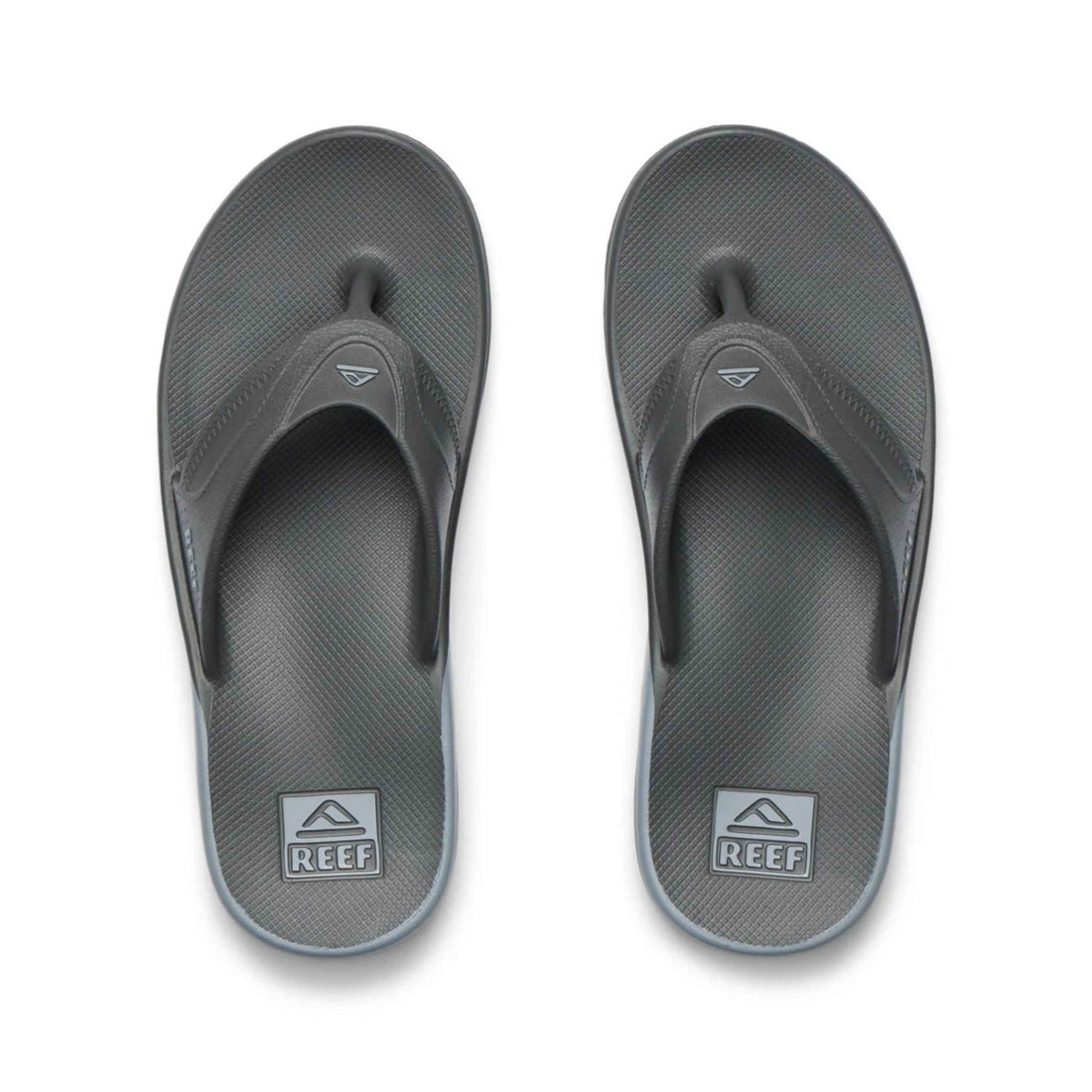 A pair of dark gray Reef brand flip-flop sandals shown from a top-down view on a clean white background.