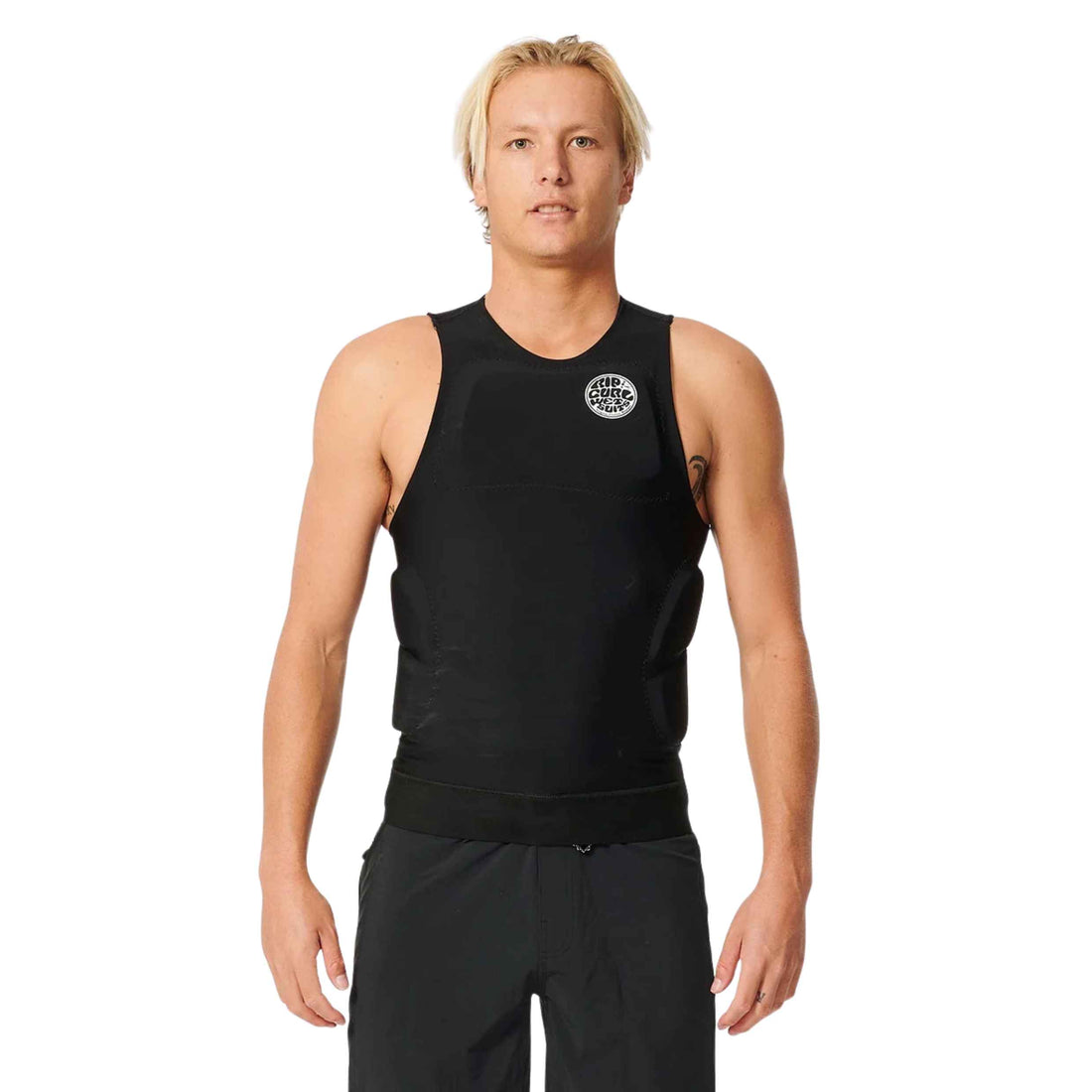 A blonde male model wearing a black sleeveless athletic compression vest with a circular white logo on the left chest, paired with black athletic pants, against a solid white background.