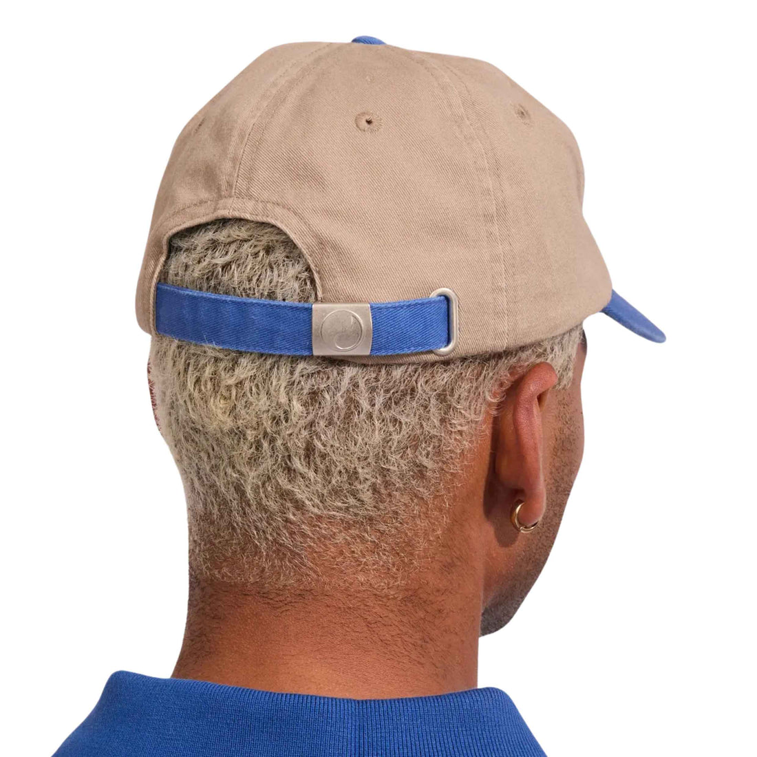 Rear view of a man wearing a beige baseball cap with a blue adjustable strap and silver metal buckle, shown against a plain white background. Worship Shadow Cherub 6 Panel Short Brim Hat at Freeride Surf & Skate Auckland NZ